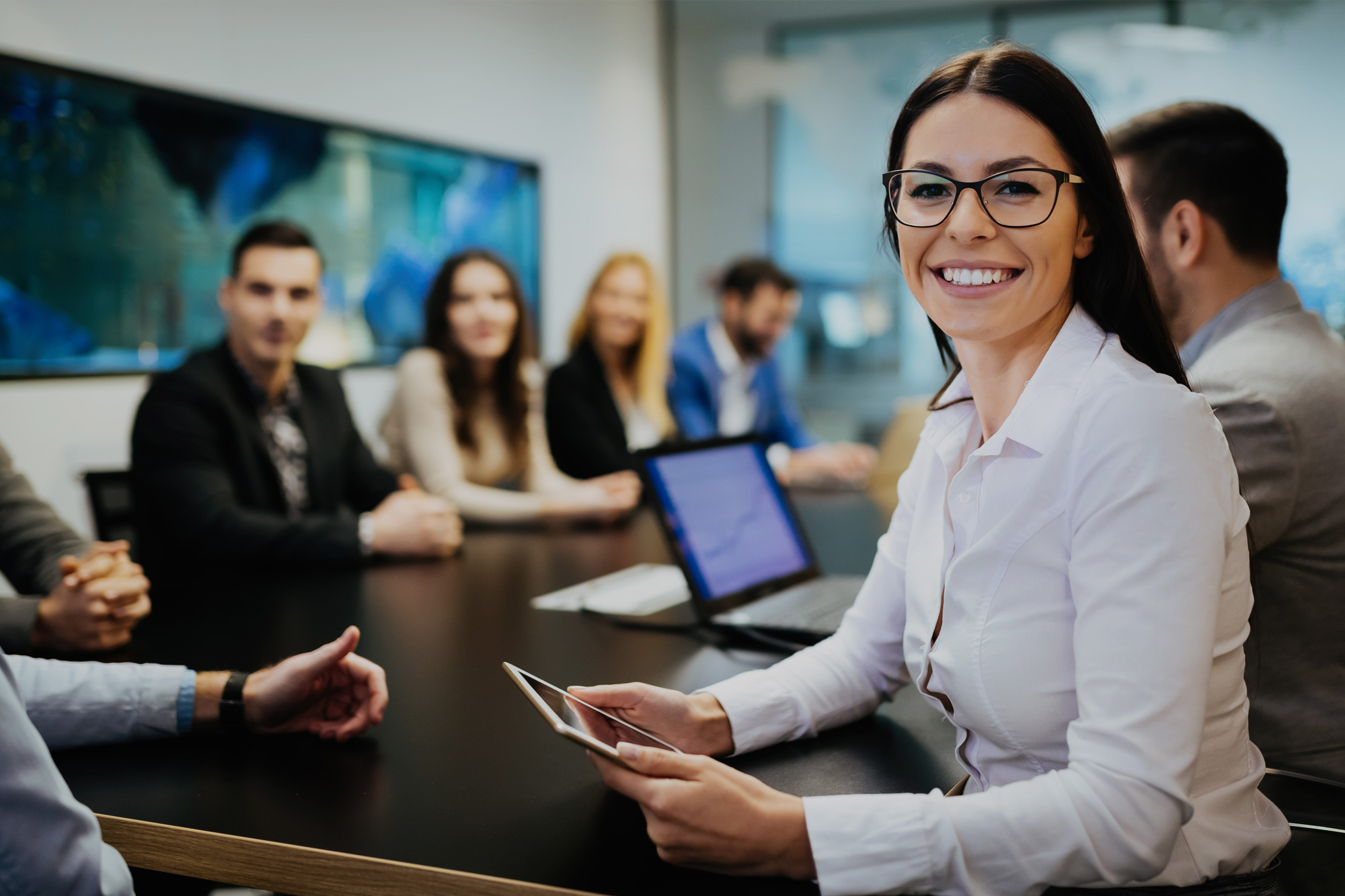 Coface logo and short descriptions on top of a group of smiling office workers gathered in a meeting room