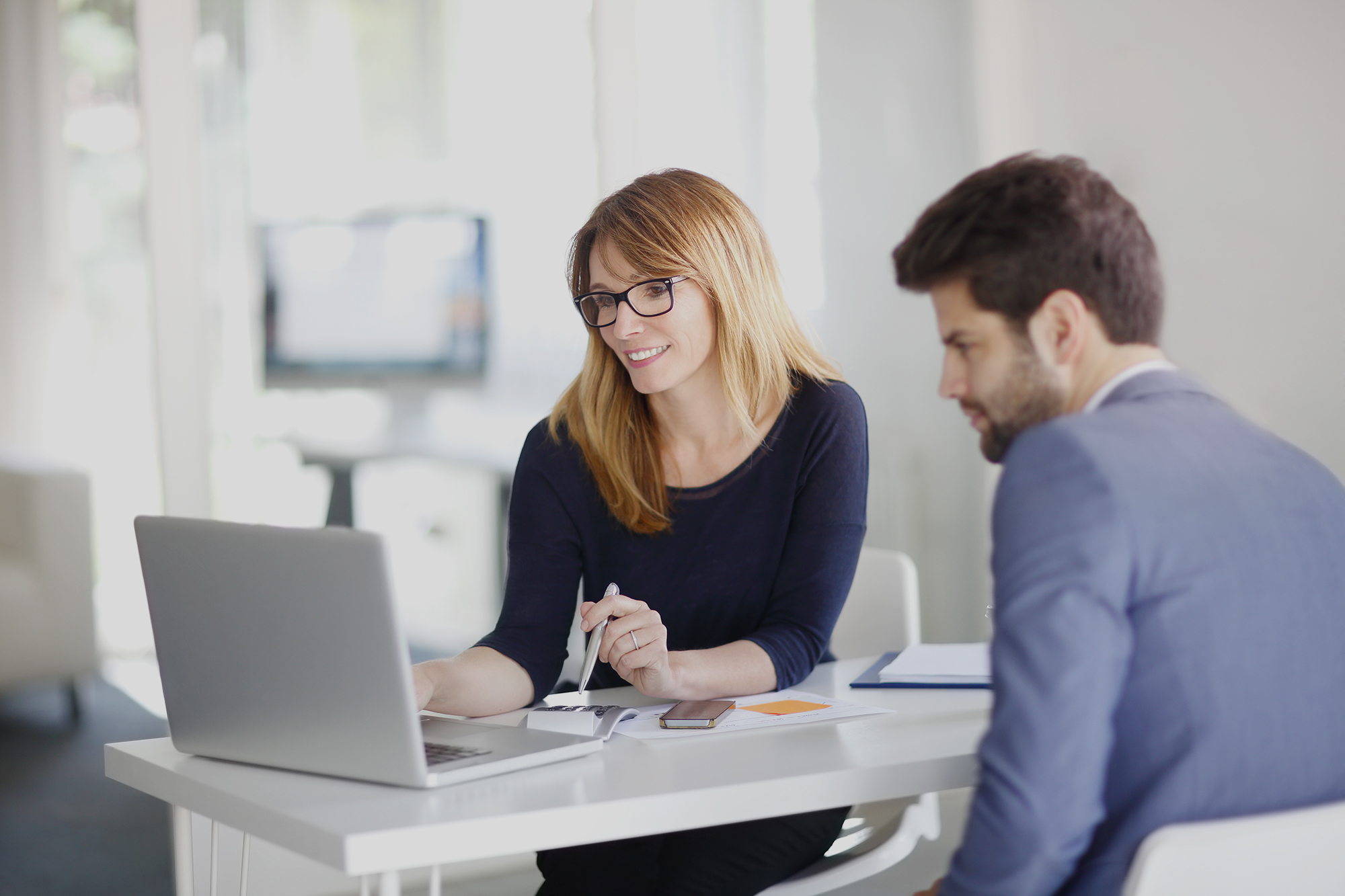 CreditDevice logo and a short description on top of two credit managers evaluating a finance report in a modern meeting room